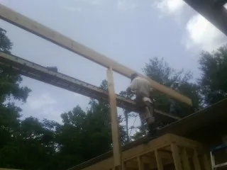 Carpenter setting a ridge beam over a new addition frame — Ice Dam Removal by Roofing Brothers in Eldena