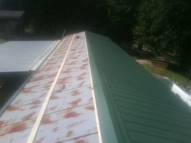 Old rusted panels beside newly installed green metal roofing — Wind Damage Roof Repair by Roofing Brothers in Eldena
