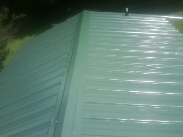 New green metal panels meeting at the ridge of a roof — Flat Roof Repair work by our crew in Eldena