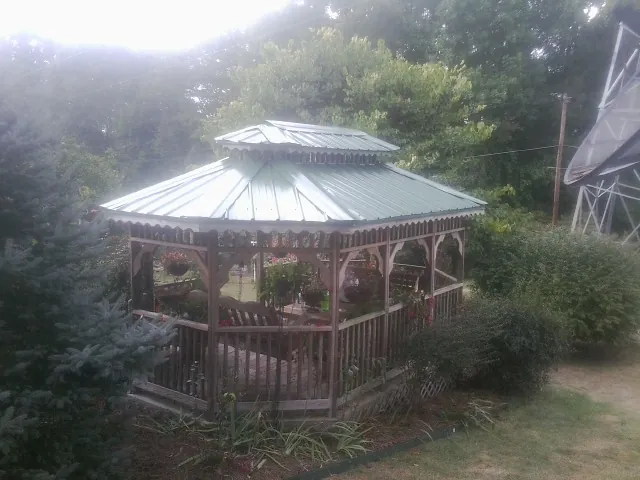 Green metal roof on a backyard gazebo surrounded by garden beds in Eldena