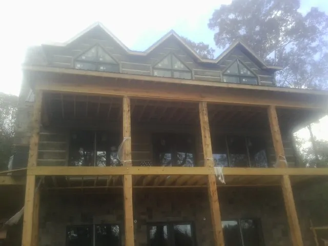 Dormers and porch framing on a large log home under construction — Roof Coating work by our crew in Eldena