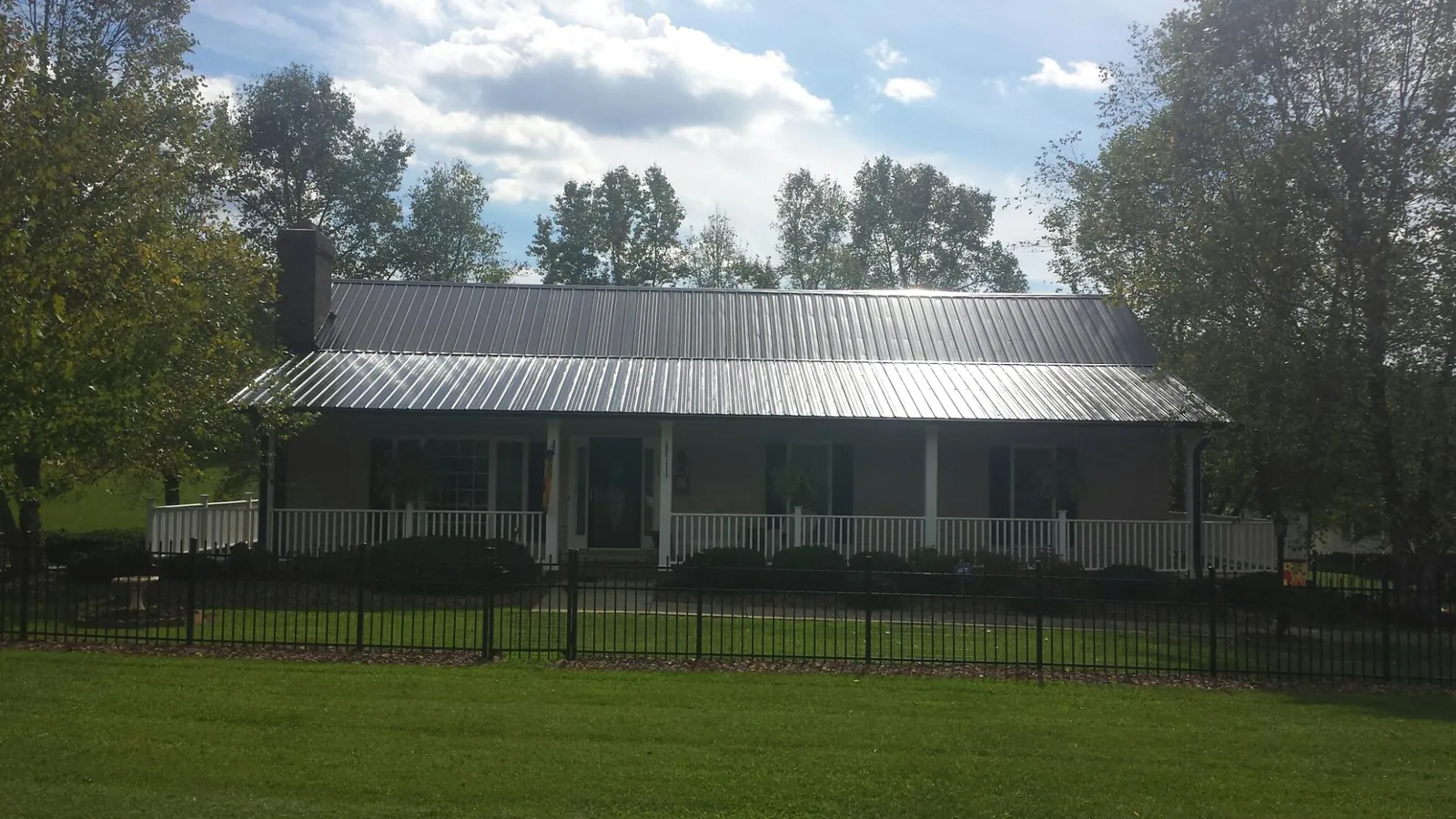 Gray metal roof on a brick ranch with a full width front porch — Gutter Guard Installation work by our crew in Eldena