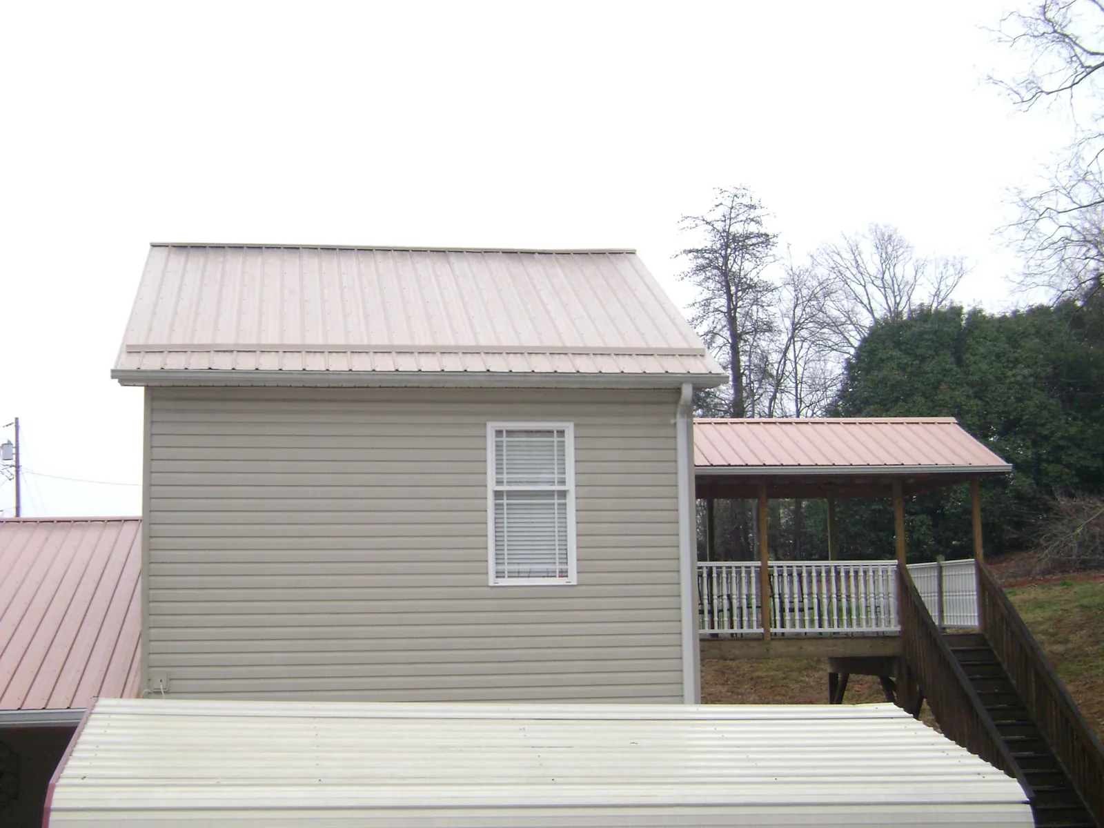 Tan metal roofs on a two story addition and attached porch, from a Roof Replacement job in Eldena