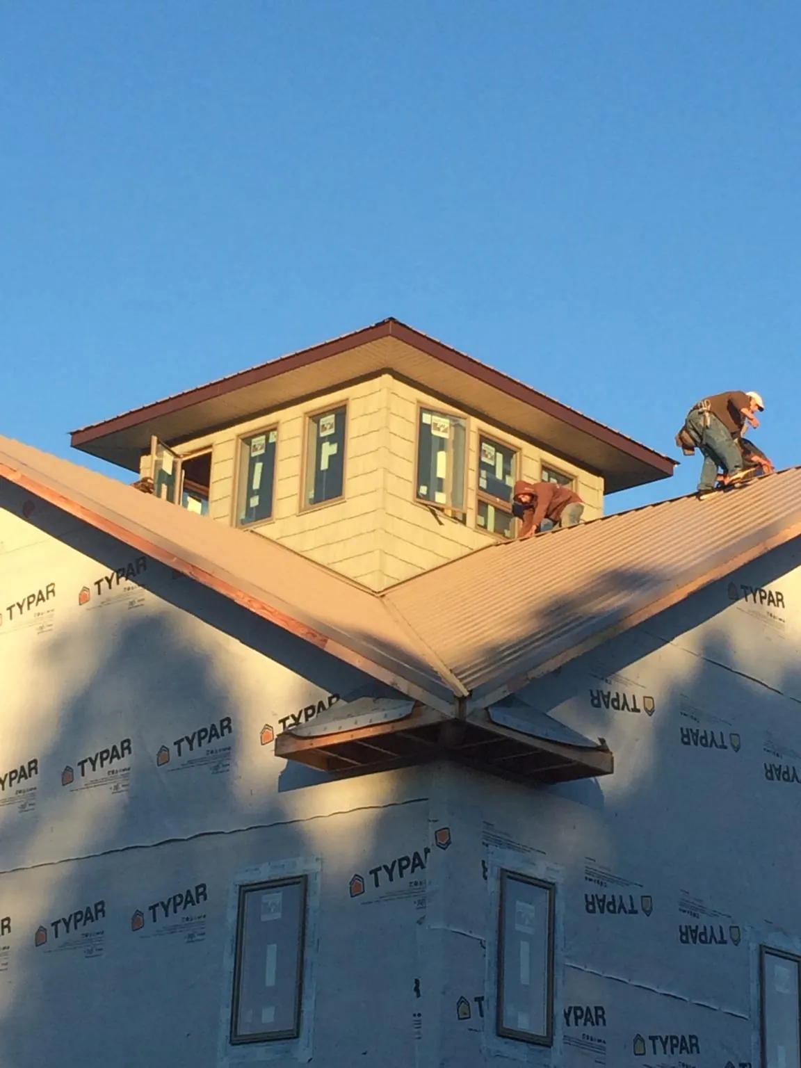 Roofers working around a rooftop cupola on a new metal roof at sunset — Roof Waterproofing in Eldena by Roofing Brothers